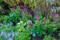 Spring border with small wooden mushroom ornament and Honesty - Lunaria annua