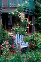 Decorative blue chair by painted house surrounded by informal planting at Keeyla Meadows, San Francisco, USA