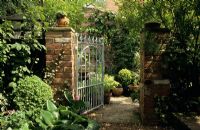 Cast iron gate in brick wall with view to small garden at Lime Tree Cottage in Surrey