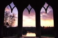 View through arched windows from Gothic Tower to lake at Painshill Surrey