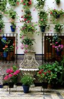 Courtyard garden with painted wallmounted containers and water fountain in Cordoba Spain