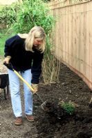 Woman turning the soil in flowerbed in autumn