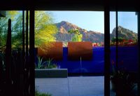 Patio with water feature on colourful painted wall and view to mountains
