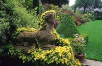 Sphinx statue overgrown with Hedera helix 'Buttercup' - Ivy at The Dillons garden in Dublin