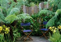 Blue canvas deckchairs on raised deck with Dicksonia antarctica at Hideaway Garden at Hampton Court Flower Show 2004