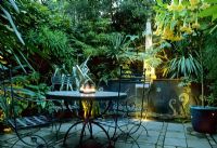 Garden lighting on terrace with metal furniture and large containers