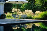 Decking with furniture and umbrella by reflective pond