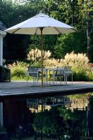 Large pond by wooden decking with furniture