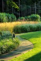 Curved path along lawn and bed with  Miscanthus floridulus, Calamagrostis x A.Strictus, Pennisetum villosum
