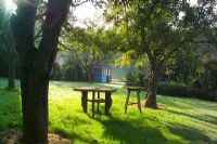 Wooden tables on lawn under trees at Highfield Hollies, Hampshire