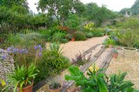 Dry gravel garden with railway sleeper steps at Meadow Nursery, Wells in Somerset  