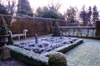 Formal parterre garden with hedge and bench in Winter frost 