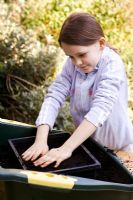 Young girl levelling compost in seed tray