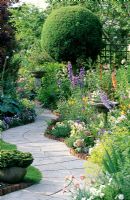 Curving path with wooden edging through colourful garden 