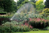 Pressure spray watering a summer border. Savill Gardens, Windsor.