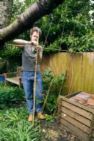 Tying willow to frame to hide compost bins