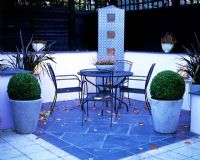 Urban courtyard terrace with furniture, paving, containers and lighting in dusk