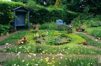 Wildlife pond and garden with herbs and wild flowers, covered seat and brick paths at Fairfield, Surrey
