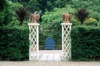 Garden entrance with wood pillars and stone ornamental birds at Kettle Hill in Norfolk