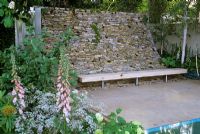 Reclaimed Cotswold stone curved wall and Oak bench  at Barnsley House Spa Garden 