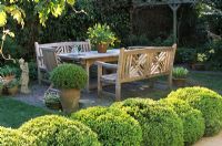Wooden furniture on patio with topiary
