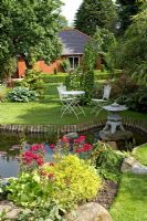 Suburban garden with pond and seating on lawn at Cypress House in Dalton