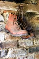 Old gardening boots hanging in shed from a rusty nail