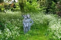 Statues hidden amongst cow parsley at edge of garden, Barnsley House Gardens, Glos - Former garden of Rosemary Verey 

