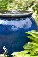 Bubble fountain in a blue glazed ceramic pot with Hosta leaves. 