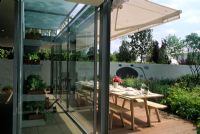 Glass garden building and decked patio area with shade canopy above