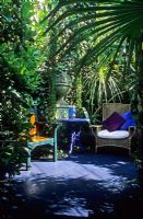 Secluded seating area amongst dense planting in small garden in Brighton