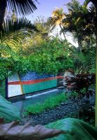 Tropical garden with water feature and pebble beach 