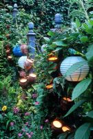 Small urban town garden - Posts adorned with containers with lights inside