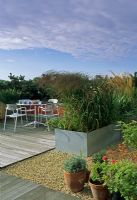 Urban contemporary roof garden with metal containers of grasses used as dividers and  bistro style table and chairs