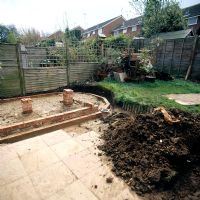 Small garden before makeover with conservatory foundations, earth mound on patio and lawn - Harpenden, Hertfordshire