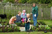 Women and children planting young box plants in new parterre garden - Pannells Ash Farm, Essex - Pannells Ash Farm, Essex
 
