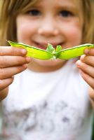 Young girl showing empty pea pod after eating the peas