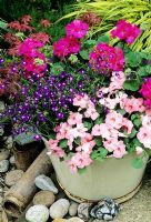 Old recycled enamel tin bowl in Summer with Impatiens - Busy Lizzies, Lobelia and Pelargoniums in brightly coloured theme 