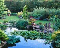 View across the lily pond to wooden pontoon with standing stones