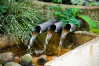 Water feature with three pipes spilling water into a rill at Wingwell nursery,  Rutland
