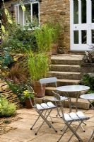 Patio with metal table and chairs in front of steps leading to white door at Wingwell nursery, Rutland