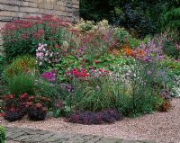 Colourful herbaceous perennial border in gravel next to path at Mayroyd Mill House, Yorkshire. Design Richard Easton and Steve Mackay. 
