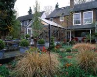 Suburban garden with conservatory and verandah. Gravel garden with Stipa arundinacea and Tulipa