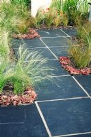 Stipa tenuissima and Sempervivum planting with black square stone paving - RHS Tatton Park Flower Show 2006
