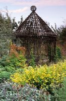 A rustic, woven twig summer house in early autumn