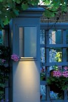 Blue painted trellis and post with light mounted on it and Pink Pelargonium