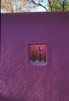 Conceptual Luis Barragan inspired garden with minimal planting of Cacti in room viewed through window in purple painted wall - El Paso, Texas USA 