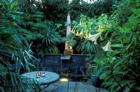 Small Town Garden with mosaic table and chairs - Brugmansia datura in pots