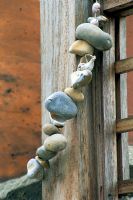 String of sea-worn pebbles wrapped around a wooden post in designer Stephen Woodhams' own roof garden.