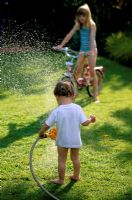 Children playing with a hosepipe in the garden